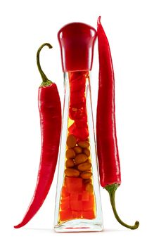 Red hot pepper in pods around the bottle with pickled vegetables on white background