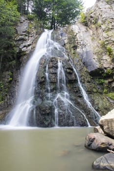 Waterfall comes out of a huge rock, Bucias Waterfall in Eastern Romanian Carpathians.