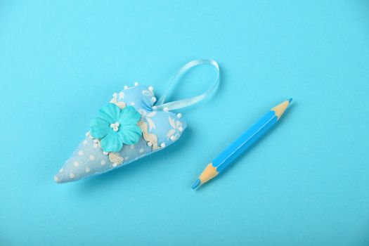 One small textile heart with mulberry paper flower and ribbon on tender blue background