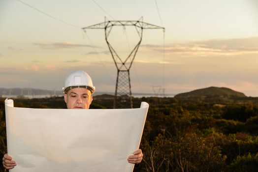 Electrical Engineer, Controls Power Line and wind turbines at sunset outdoors in the countryside