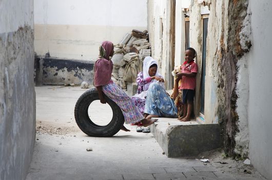Zanzibar, Tanzania - January 1, 2016: African Muslim women holding baby her arms and her children on the street of Stone Town in Zanzibar