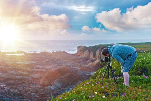 Nature Photography. Photographer on the Ocean Cliff Taking Sunset Pictures.