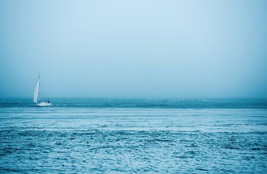 Yacht and the Sea. Small Boat on the Ocean with Foggy Weather.