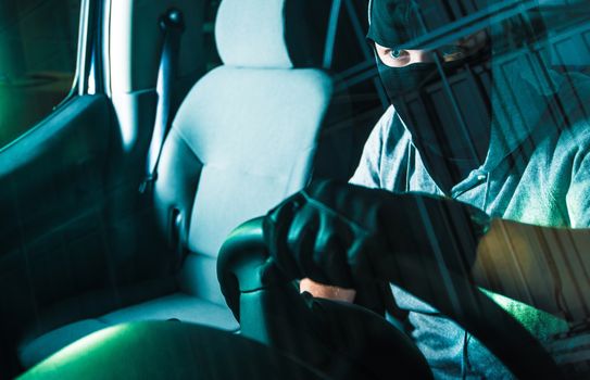 Auto Theft Carjacking. Young Caucasian Male Carjacker in Black Mask Driving Stolen Car. Motor Vehicle Theft Concept Photography. Grand Auto Theft.