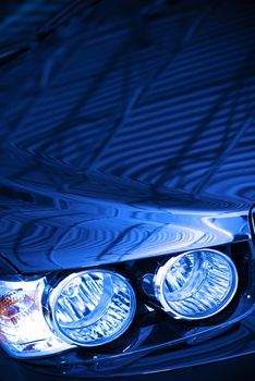 Blue Car Concept Photo. Blue Body Compact Car Hood and Headlight Closeup.