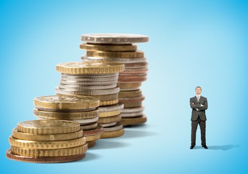 Businessman in front of stacks of coins on blue