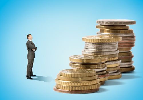 Businessman in front of stacks of coins on blue