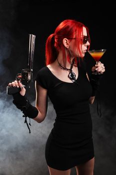 Sexy red hair woman with a gun and a cocktail
