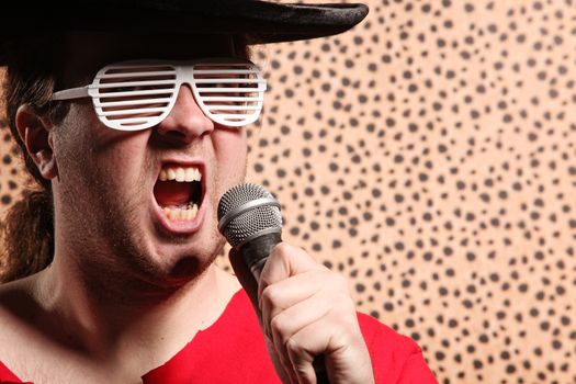 Crazy rock and roller singer with a big black hat, party glasses in front of a cheetah skin background