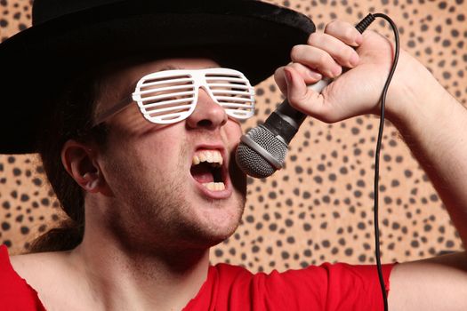 Crazy rock and roller singer with a big black hat, party glasses in front of a cheetah skin background