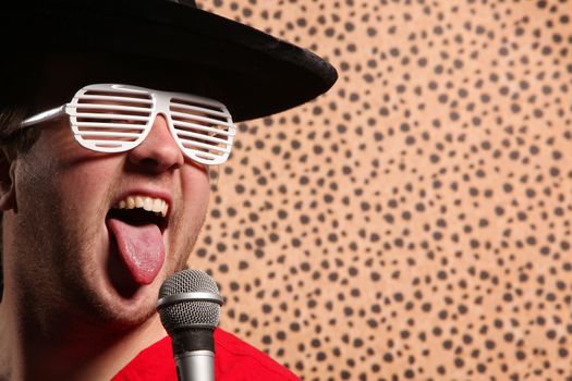 Crazy rock and roller singer with a big black hat, party glasses in front of a cheetah skin background