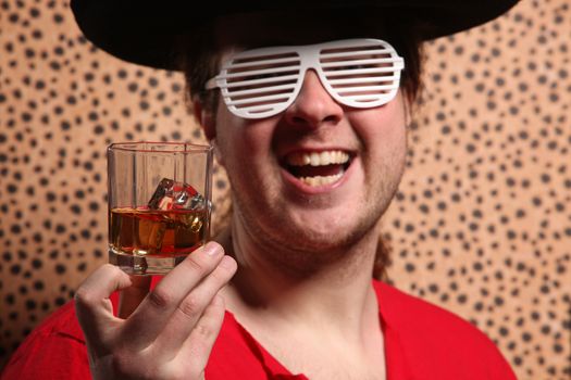 Crazy rock and rollerer with a big black hat, party glasses and a glass of whiskey in front of a cheetah skin background