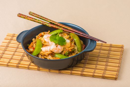 Serving of shrimp pad thai on a bamboo mat.