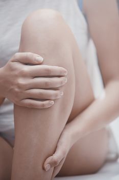 Woman doing leg massage and applying moisturizing cream