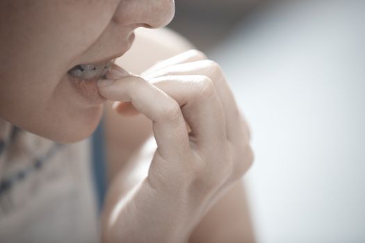 Close-up view on the woman biting nails