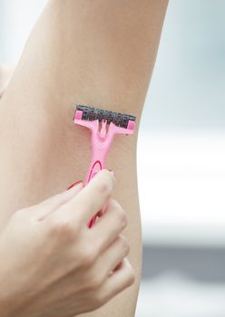 Woman shaving armpit. Close-up vertical photo