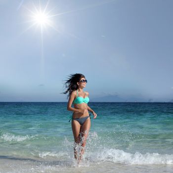 Young attractive woman in bikini run from sea to beach