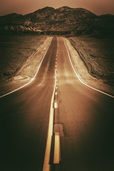 Desert Road To Nowhere. Vertical Dark Sepia Color Grading Road Photo. Death Valley Road, California, United States.