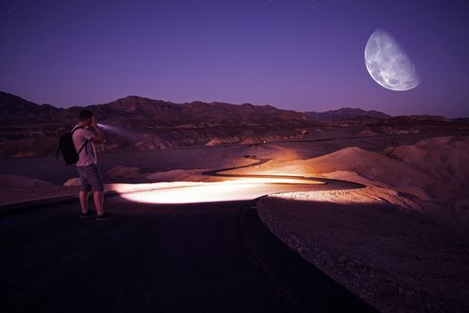 Hiker with Powerful Flashlight on Death Valley Trail During Starry Night. Night in Death Valley National Park, California, United States.