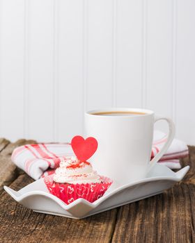 Red velvet cupcake served with a cup of coffee.