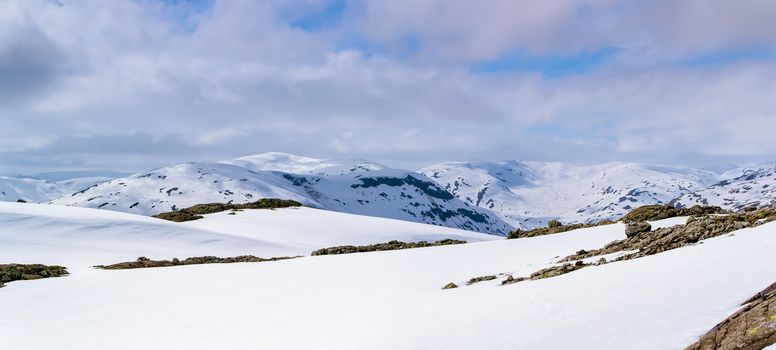 Winter landscape of mountain range. Clean snow, purple clouds. Norway