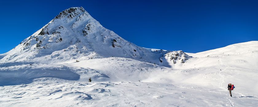 Tourist photographs the top of the mountain. The sky is clear, sunny. Winter. Ukrainian Carpathian Mountains