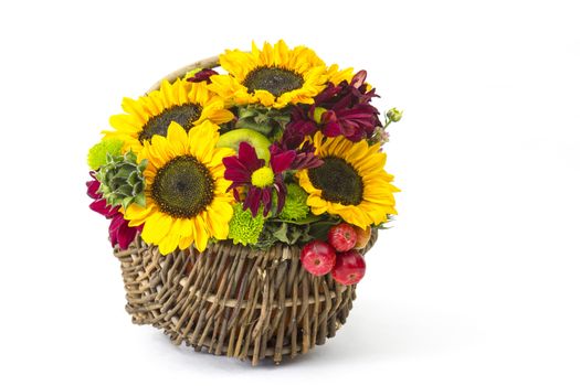 basket with autumnal flowers, berries and apples on white background