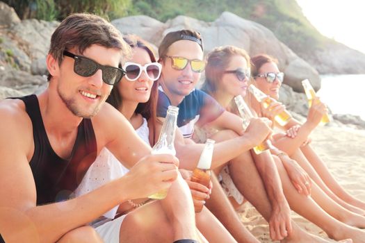 Happy young friends drinking beer on beach