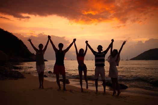 Group of people partying on beach at sunset