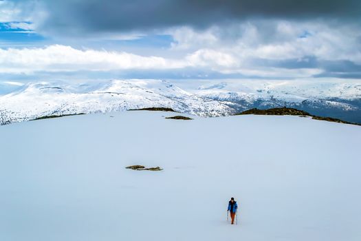 Tourist on snow field. Trekking in the snowy winter mountains. Clouds. Norway