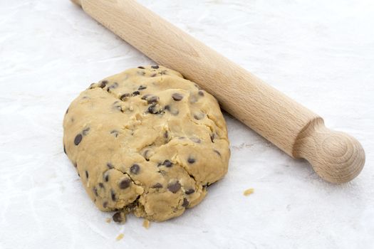 Close-up of peanut butter and chocolate chip cookie dough with a wooden rolling pin