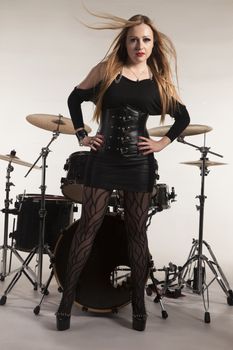 Young beautiful blonde woman standing in front of drumkit