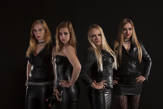 Group of young women wearing leather outfits on black background
