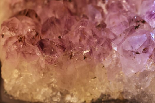 Purple and white natural amethyst geode background pattern glitters in the light.
