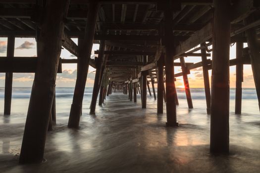 Under the San Clemente pier on the beach at sunset in the fall in Southern California, United States.