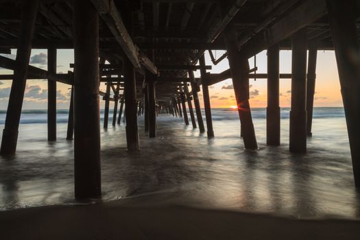 Under the San Clemente pier on the beach at sunset in the fall in Southern California, United States.