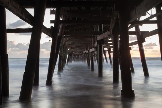 Under the San Clemente pier on the beach at sunset in the fall in Southern California, United States.