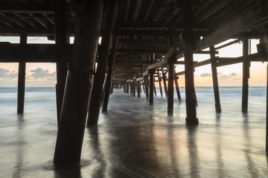 Under the San Clemente pier on the beach at sunset in the fall in Southern California, United States.