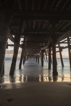 Under the San Clemente pier on the beach at sunset in the fall in Southern California, United States.