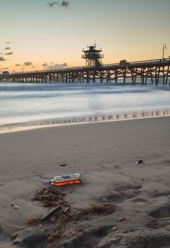 Bottle of alcohol on the beach in front of the San Clemente pier at sunset in San Clemente, Southern California, United States