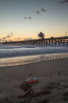 Bottle of alcohol on the beach in front of the San Clemente pier at sunset in San Clemente, Southern California, United States