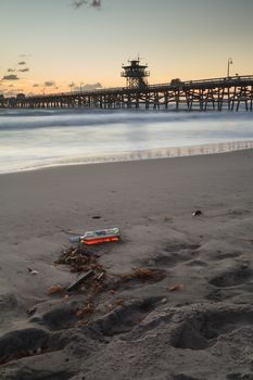 Bottle of alcohol on the beach in front of the San Clemente pier at sunset in San Clemente, Southern California, United States