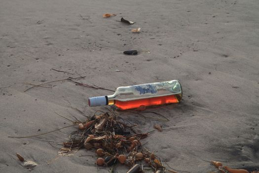 Bottle of alcohol on the beach in front of the San Clemente pier at sunset in San Clemente, Southern California, United States