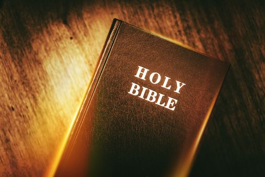 Holy Bible in Dark Browny Vintage Color Grading. Glowing Light Holy Bible 