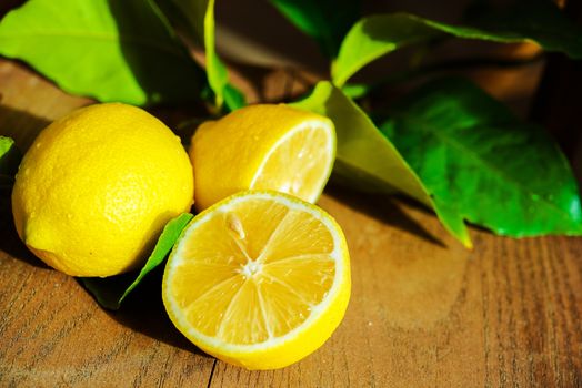 Fresh Sliced Lemon and Lemon Tree Leaves on Wooden Table.