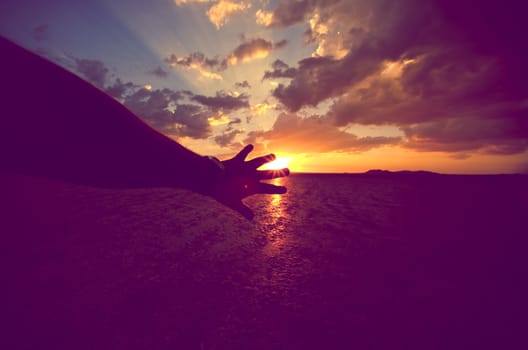 Touching the Sun. Nature and Travel Concept. Hand and the Sun. Beautiful Sunset Scenery.