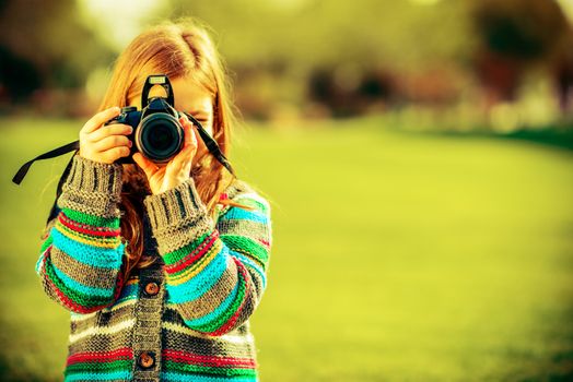 Caucasian Girl with Large Modern DSLR Camera Taking Pictures in Park.