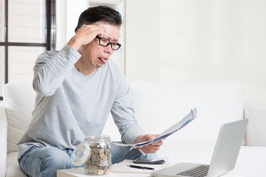 Stressed 50s mature Asian man paying bill at home. Saving, retirement, retirees financial planning concept.