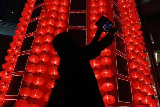 MALAYSIA, Kuala Lumpur: People walk past red lantern decorations ahead of Lunar New Year celebrations at a shopping mall in front of Petronas Twin Towers in Kuala Lumpur on January 25, 2016.