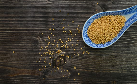 mustard seeds spoon over dark wood background